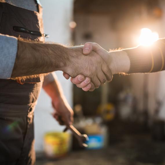 Senior mechanic handshaking with the customer,close up of human hands